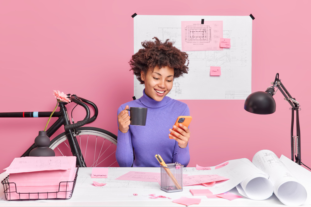 Criadora de conteúdo usando smartphone com papéis sobre a mesa, representando a necessidade de assessoria jurídica para influencers e criadores em Campinas. 