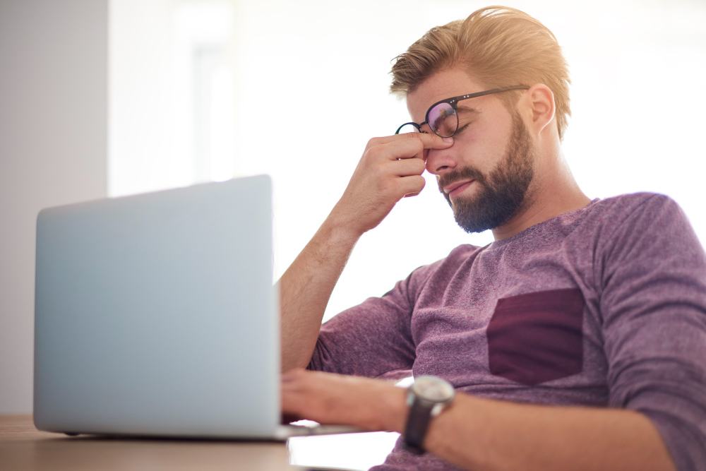 Homem preocupado diante de tarefa complexa no trabalho, representando o momento de descoberta e a necessidade de orientação jurídica em casos de uso indevido de imagem.